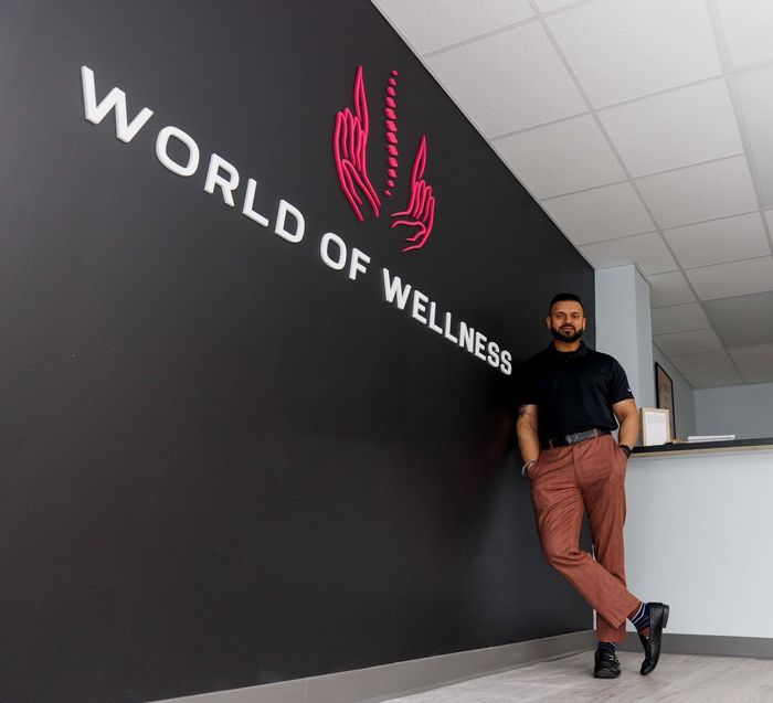a man leaning against a wall that says world of wellness