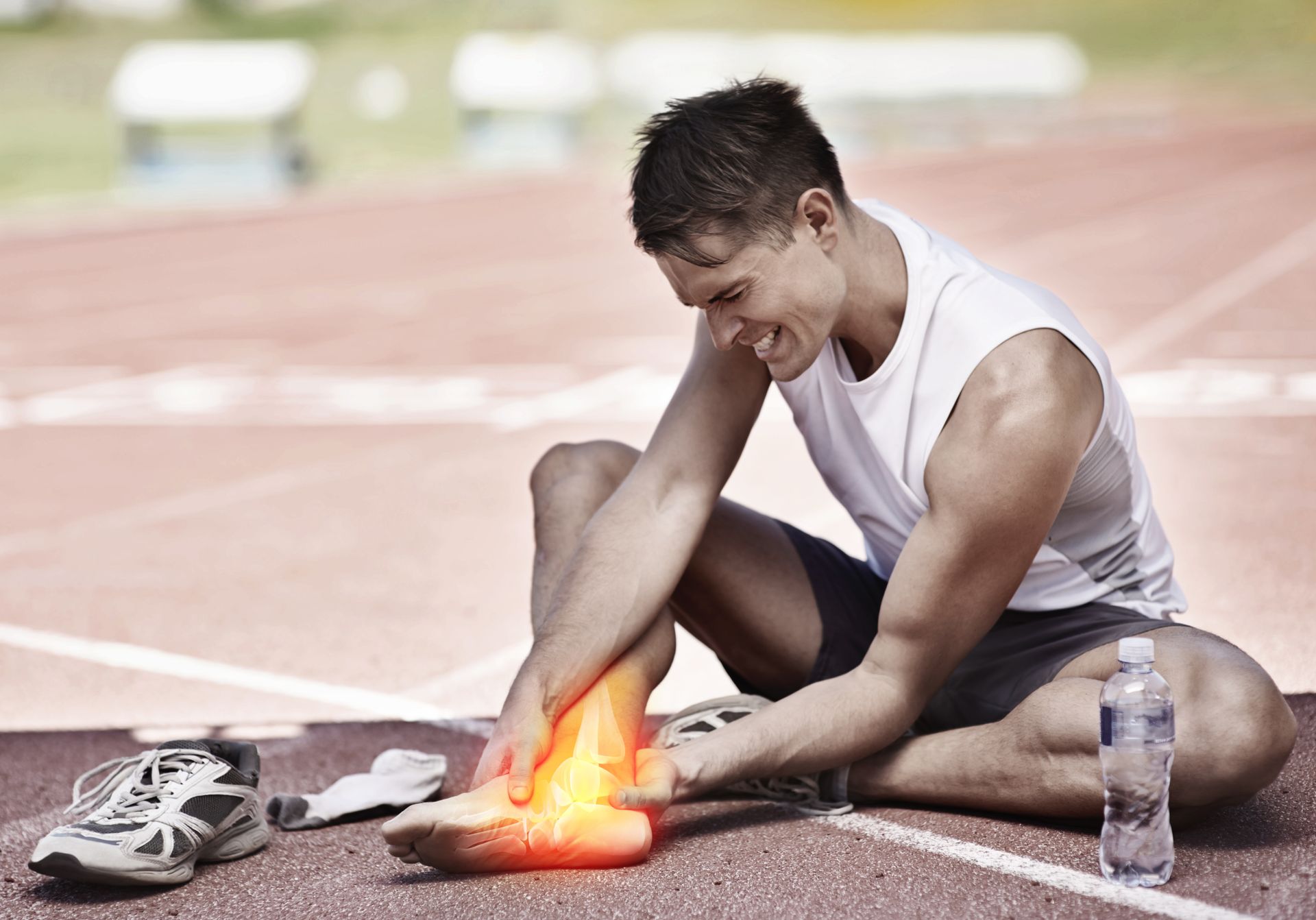 a man is sitting on a track holding his ankle in pain