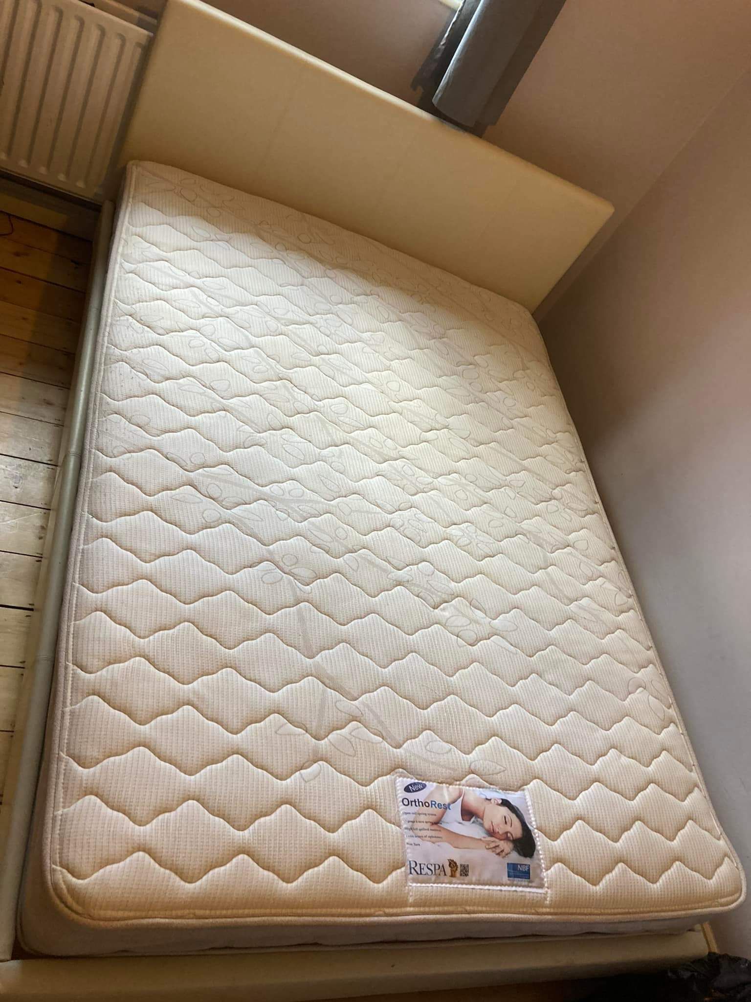 A white mattress is sitting on top of a bed in a bedroom.