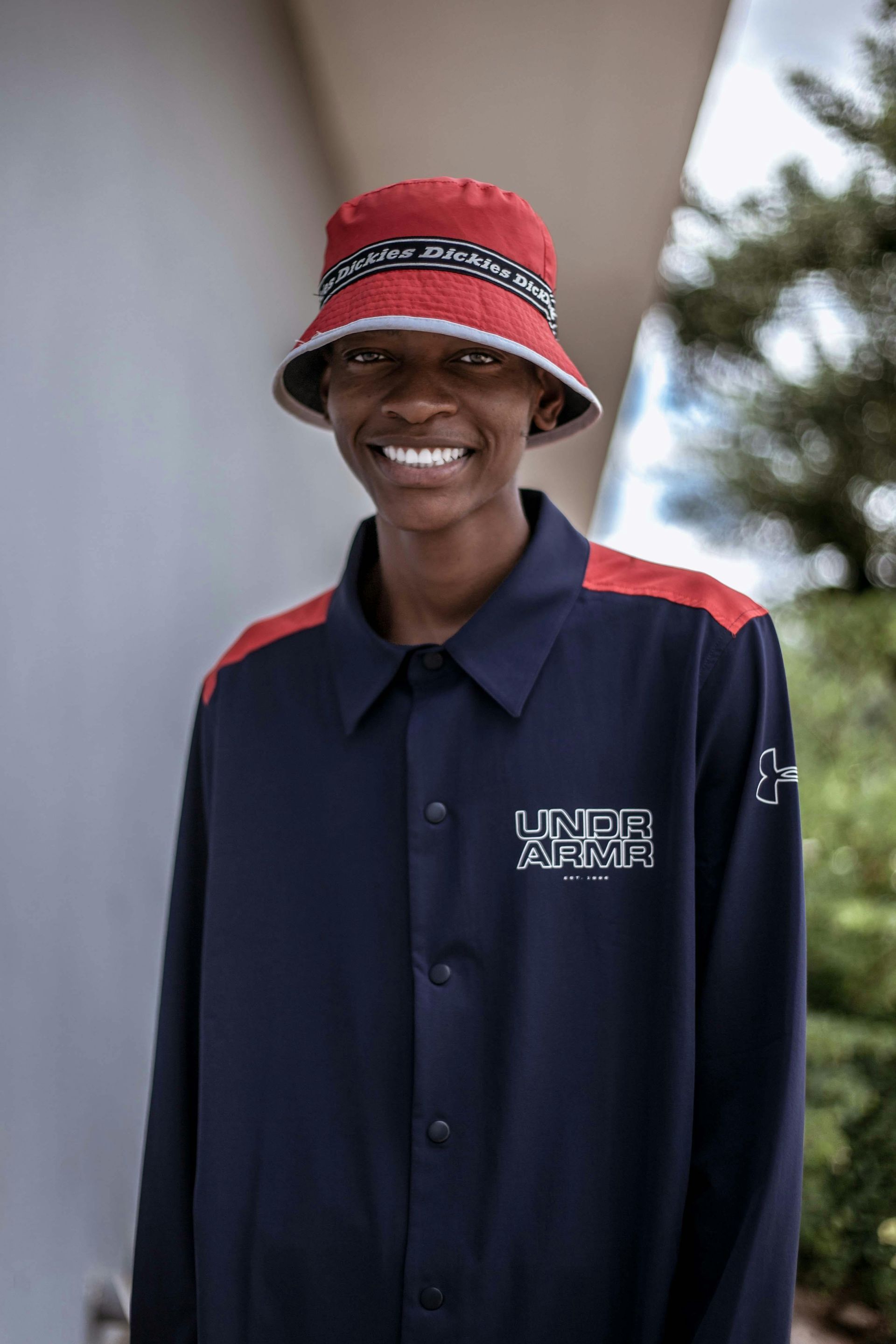 A man wearing a red hat and a blue shirt is smiling.