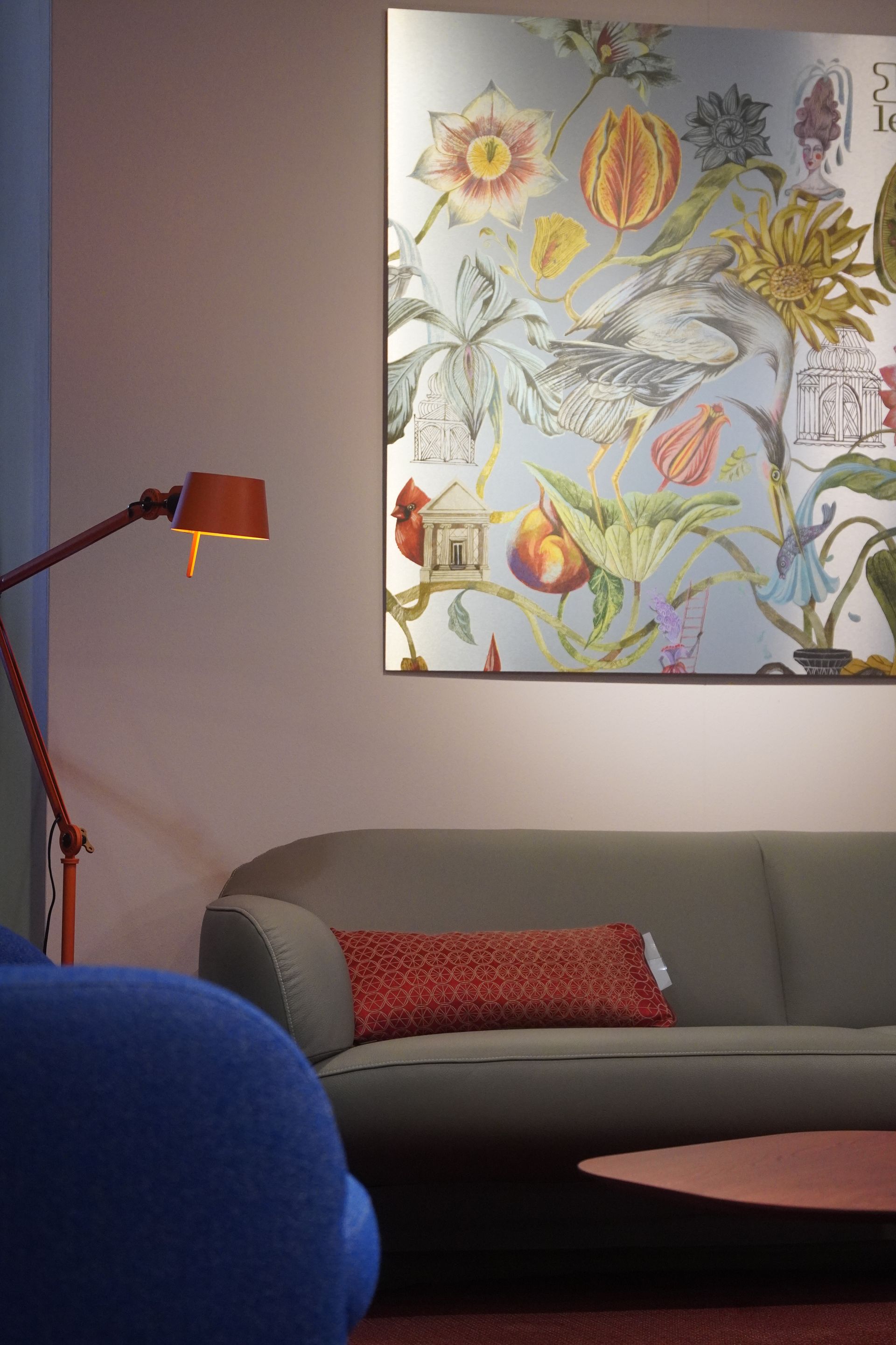 A living room with a couch a lamp and a large painting on the wall.