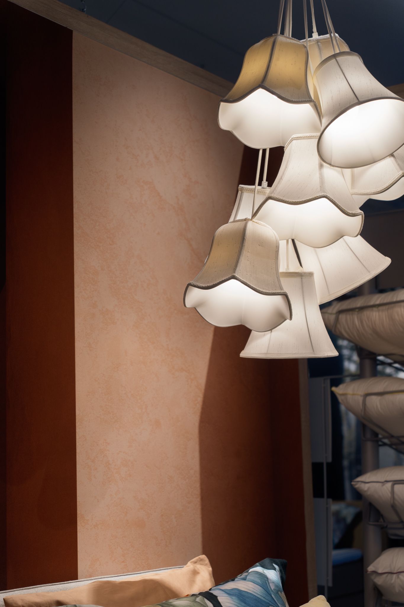 Cluster of lamps with scalloped shades, against a mottled peach wall with a dark red stripe.