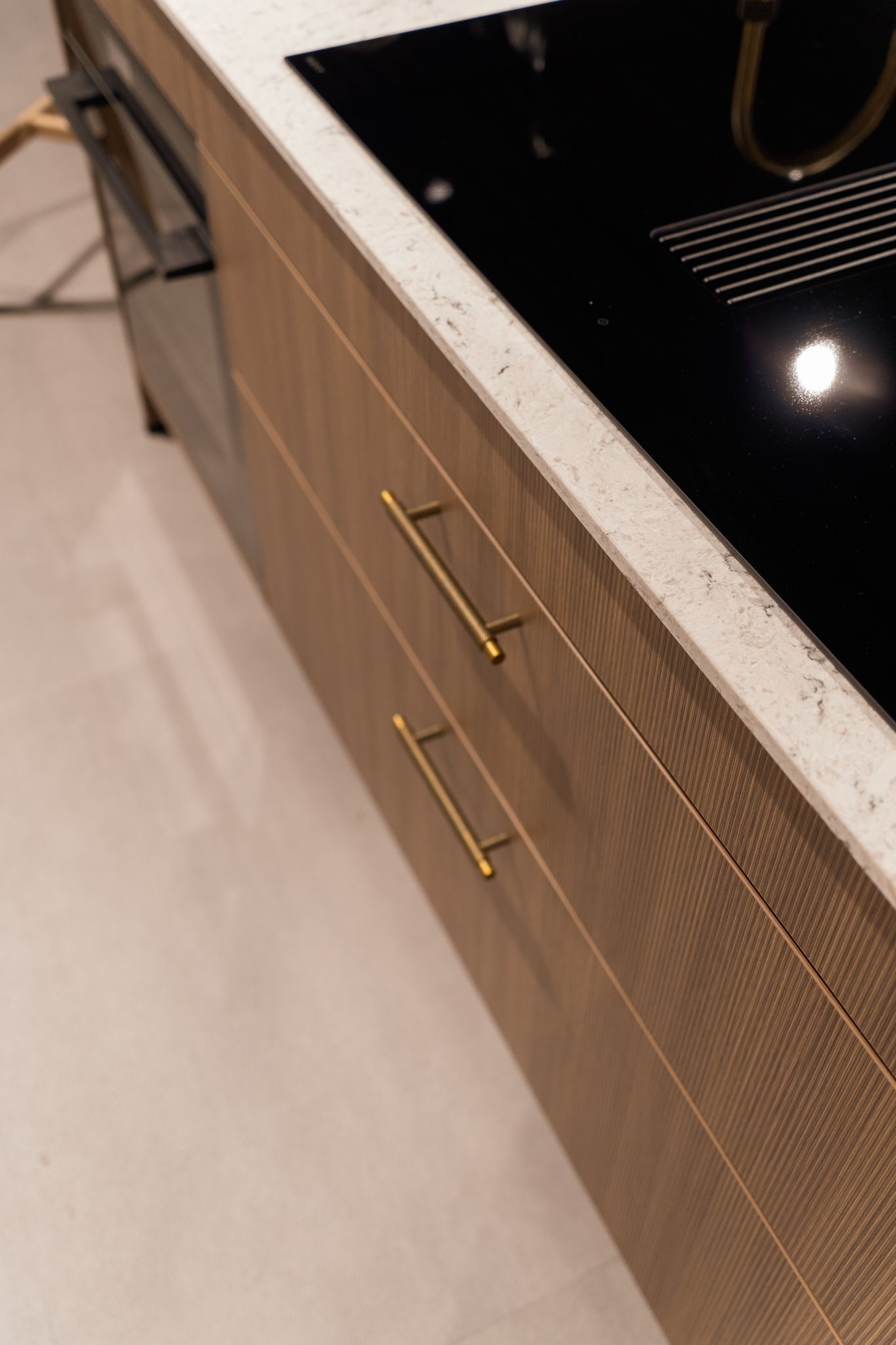 Close-up of kitchen cabinetry with brass handles and a white countertop.