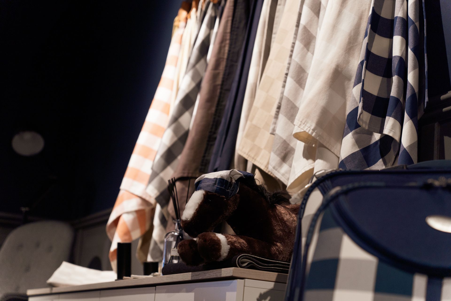 Checkered fabric hanging with a blue and white suitcase in a dim setting.
