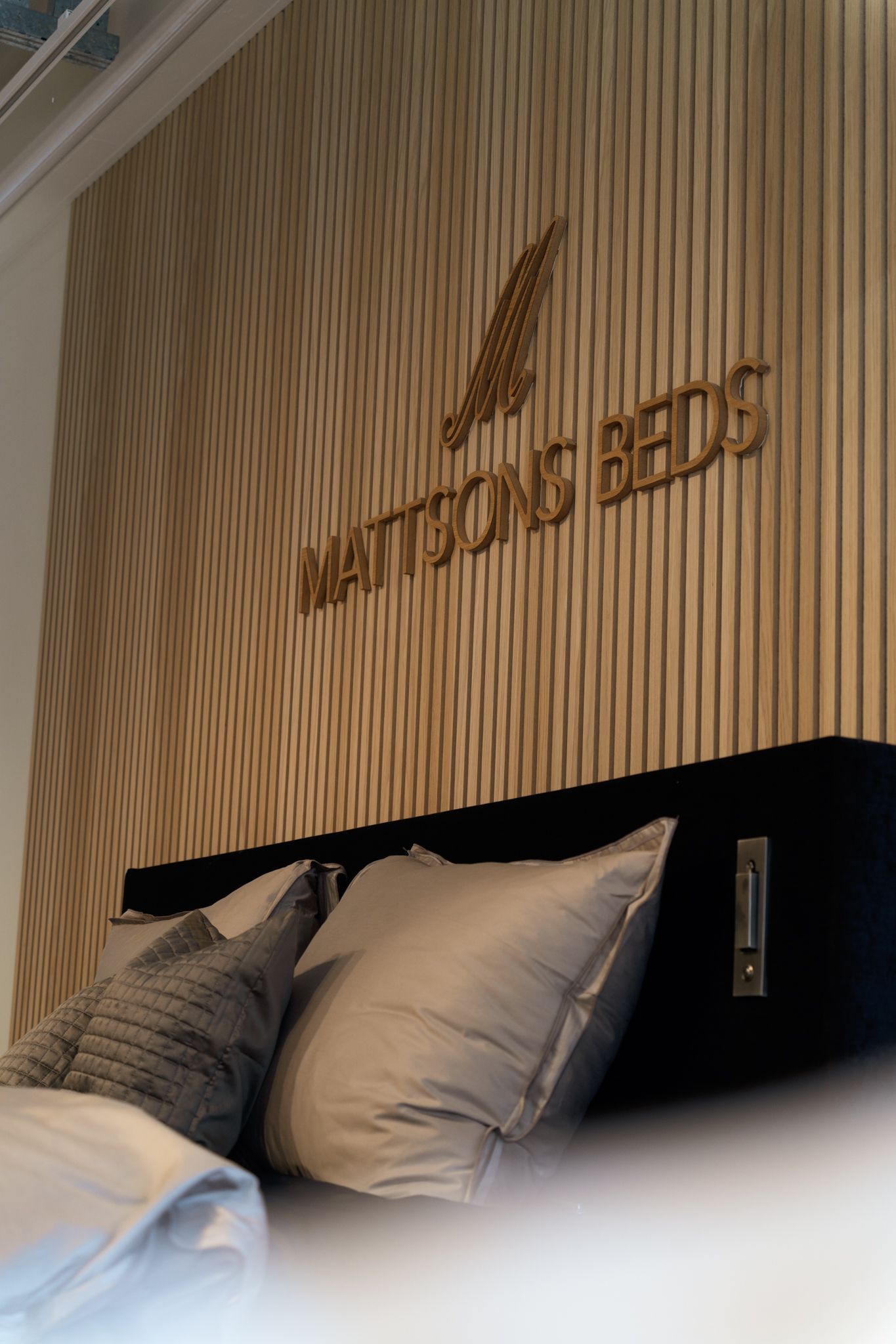 Bedroom with wooden paneling, gold logo, and pillows on a bed.