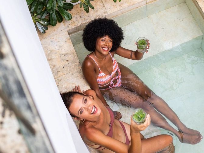 two women in bikinis are sitting in a pool holding drinks at Boho Curacao