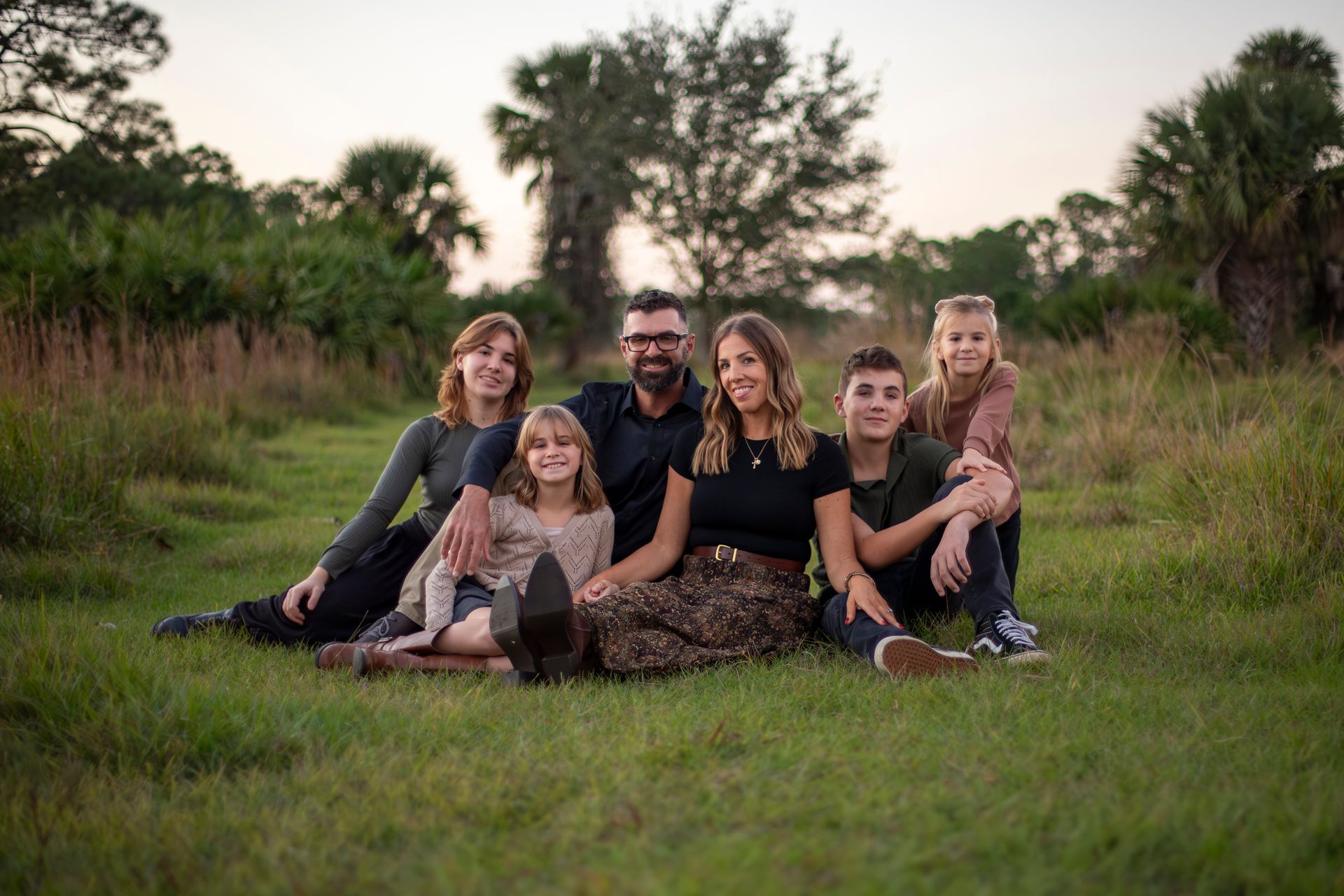 A family is posing for a picture in the grass.