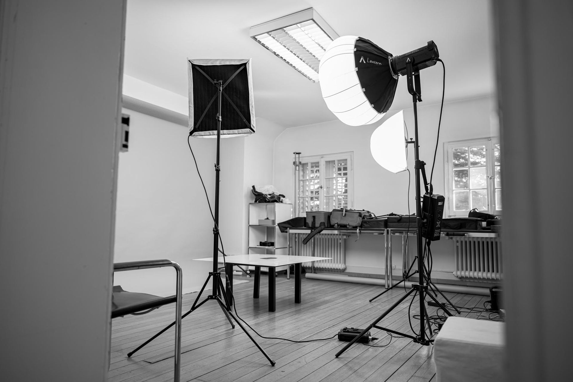 Schwarz-Weiß-Fotostudio mit Softbox-Leuchten, Stativen und Stühlen in einem hellen Raum