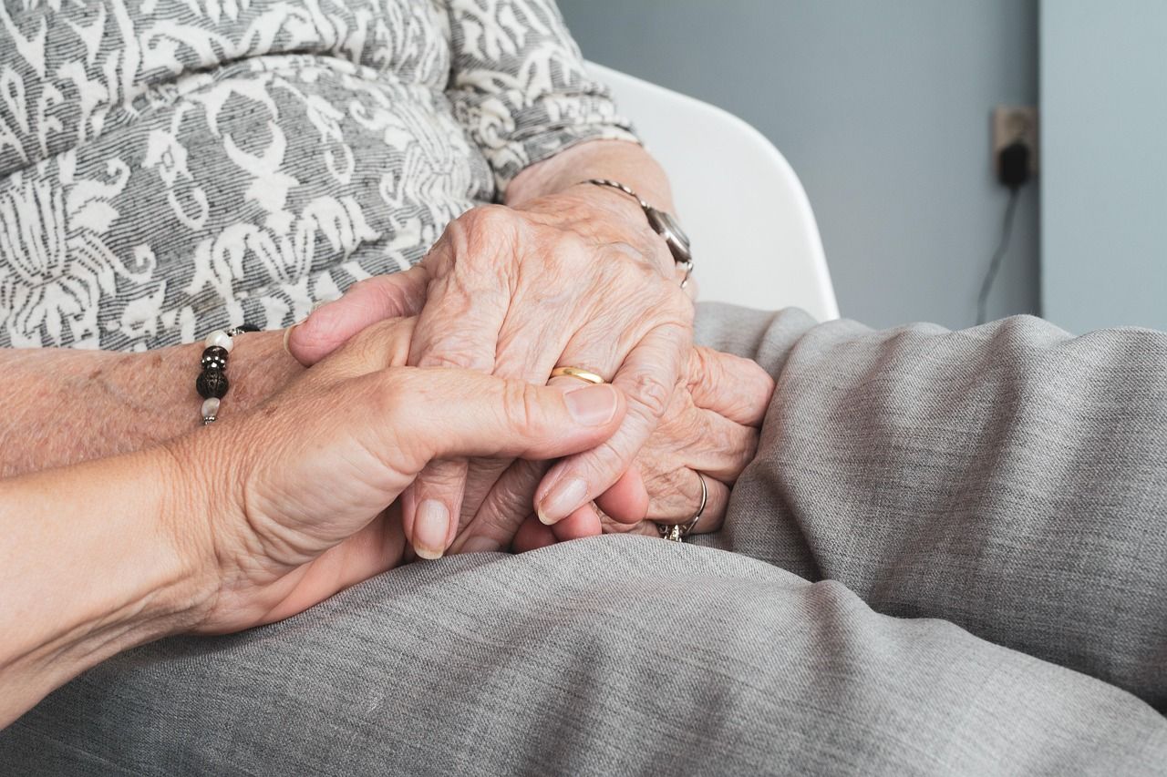 younger hand holding hand of an older woman