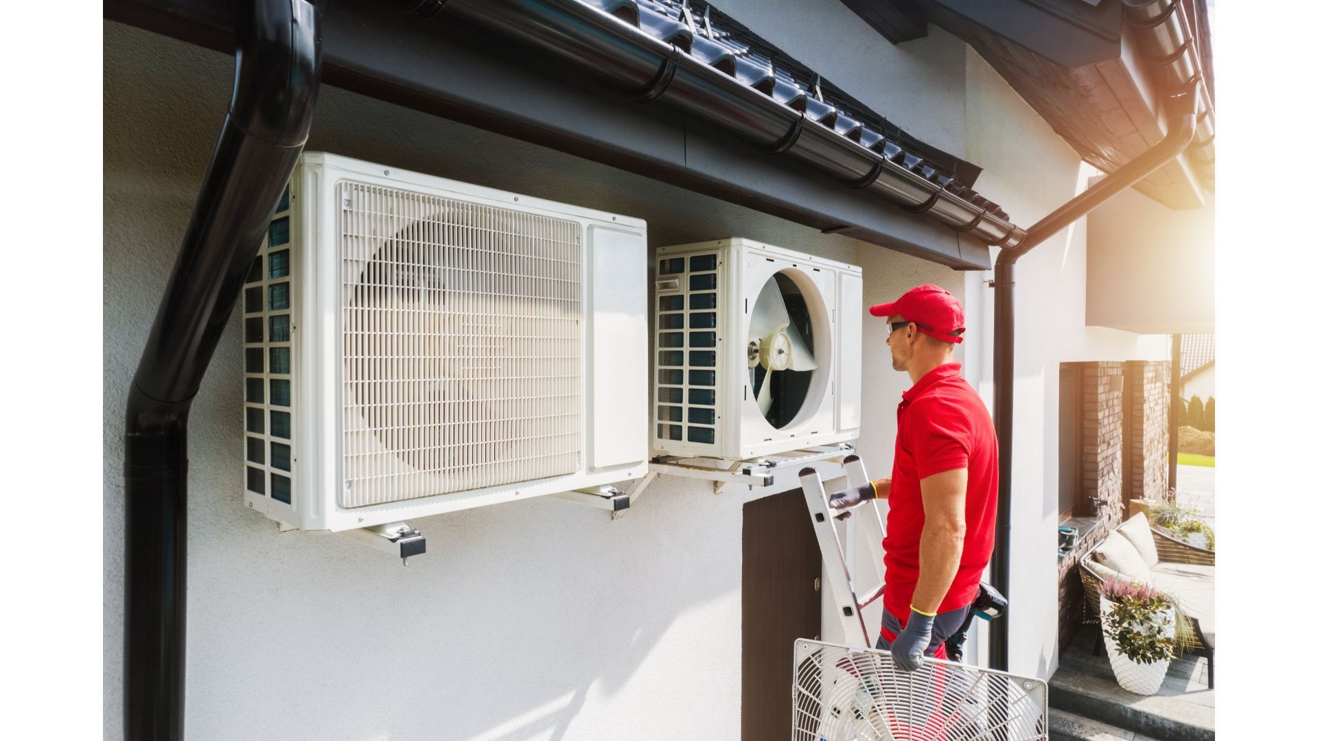A man is working on an air conditioner on the side of a building.