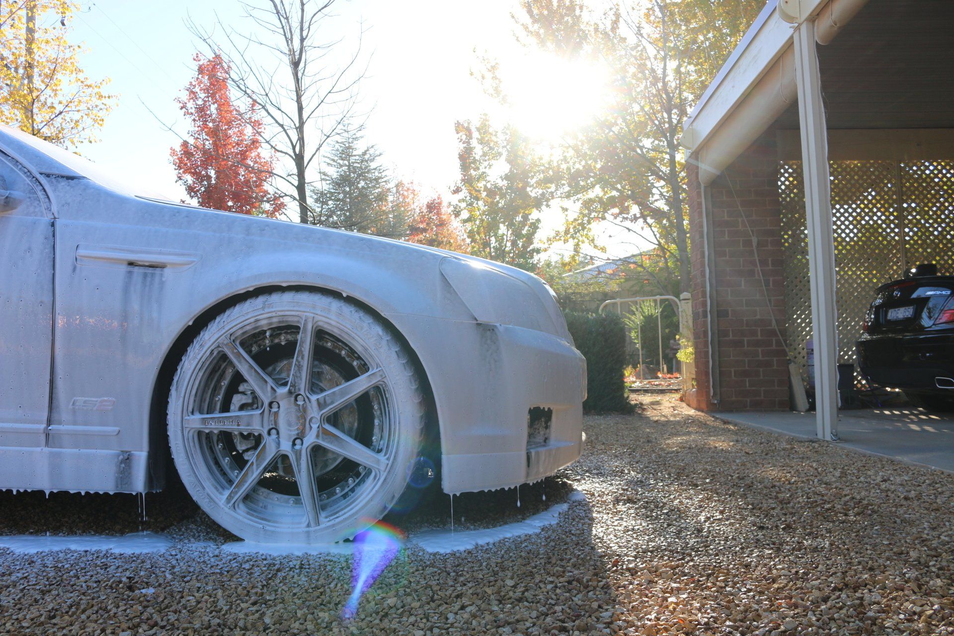A car is covered in foam in a driveway.