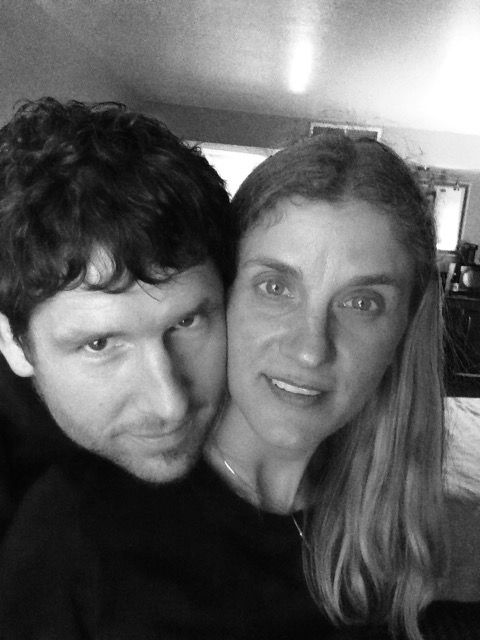 Man and woman embrace, smiling, close-up in black and white.