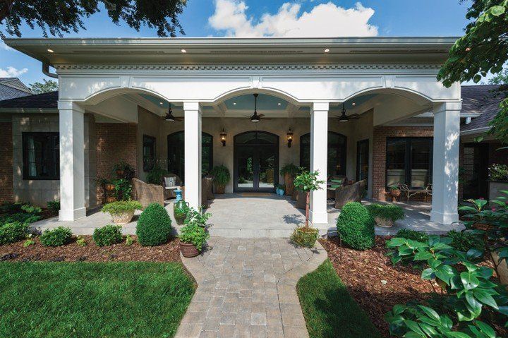 A brick house with a large porch and a walkway leading to it