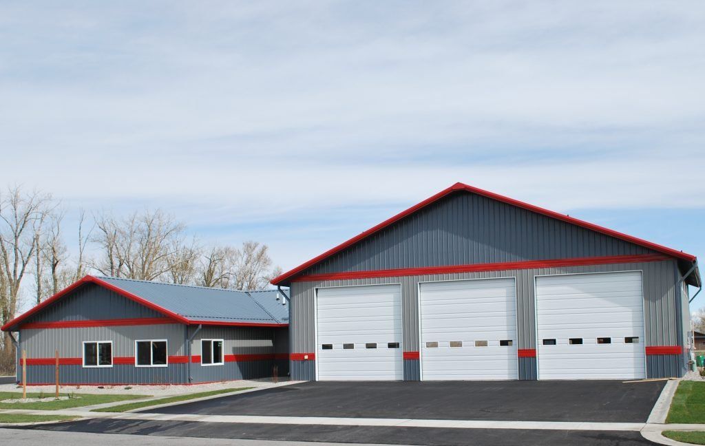 A garage with three white doors and a red roof
