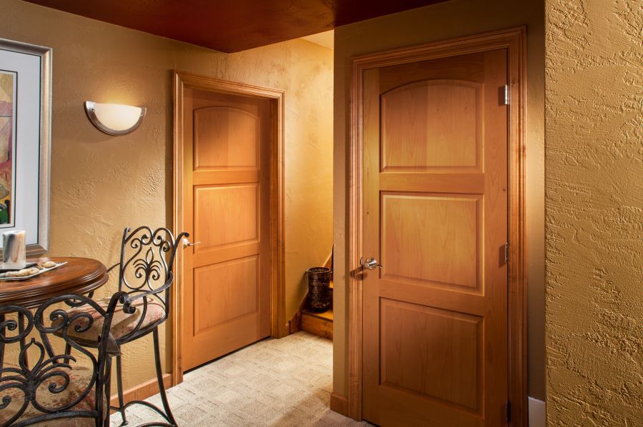 A hallway with wooden doors and a table and chairs.