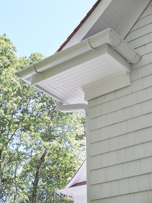 A white house with a gutter on the side of it.