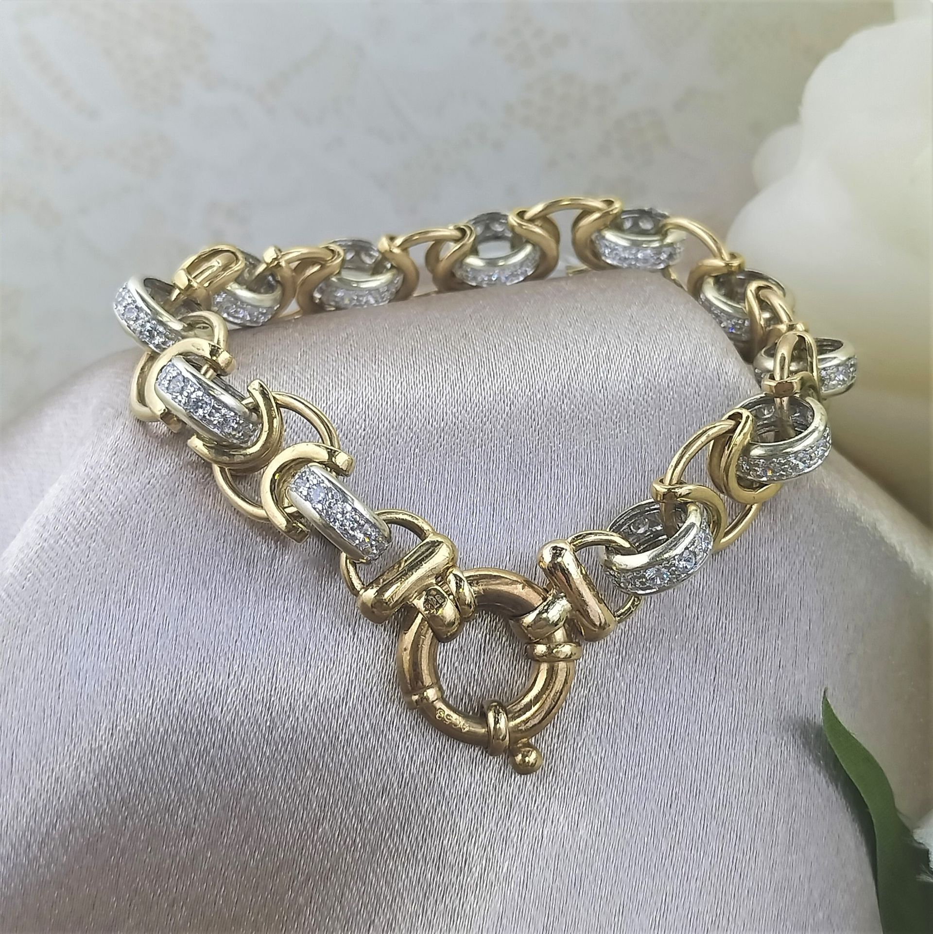 A gold and silver bracelet is sitting on a white cloth