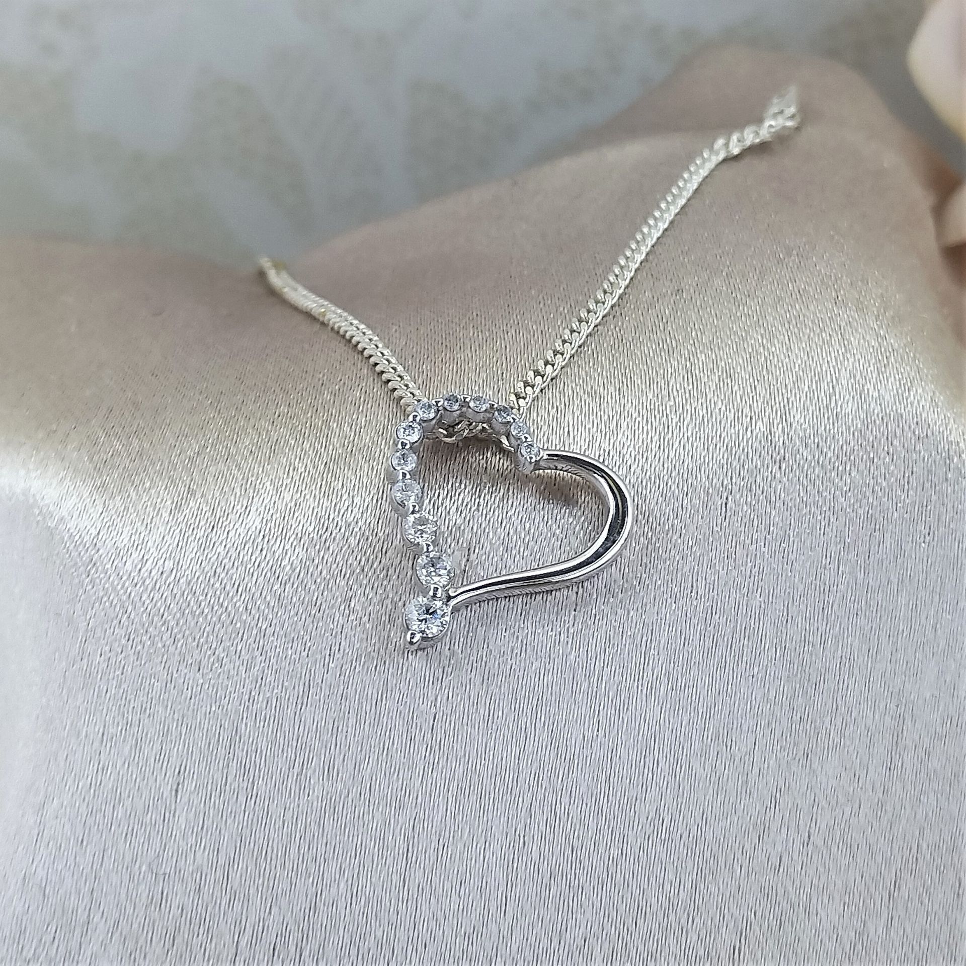 A close up of a necklace with a heart shaped pendant on a chain.