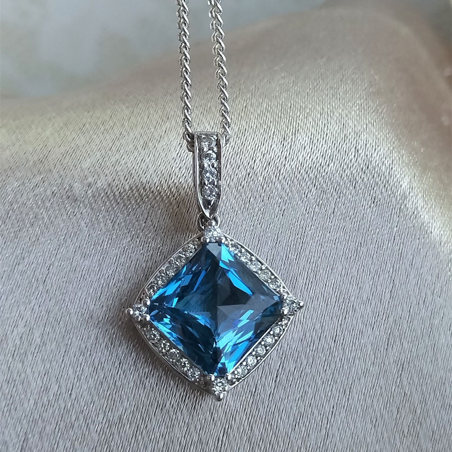 A necklace with a square blue stone and diamonds on a chain.