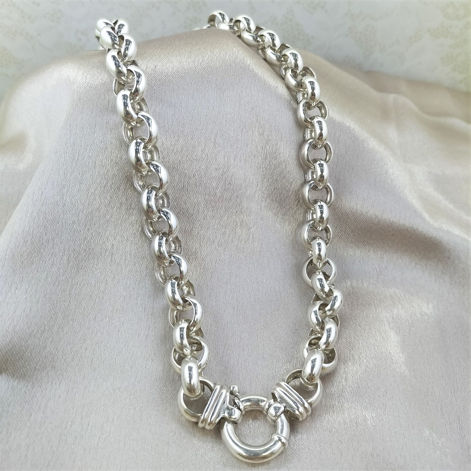 A silver chain is laying on a white cloth