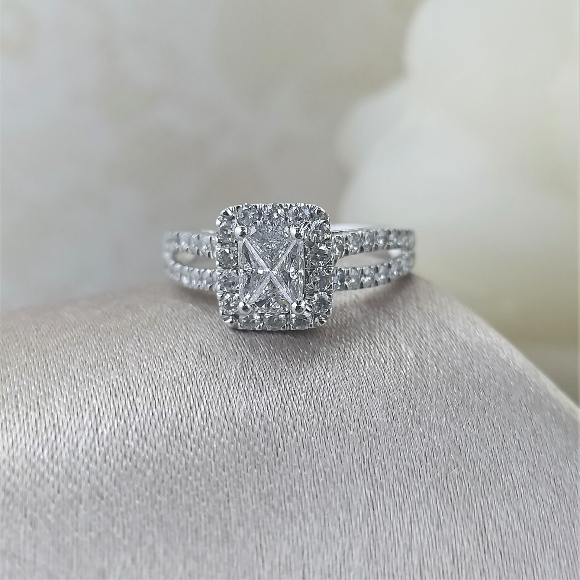 A diamond ring is sitting on a white cloth.