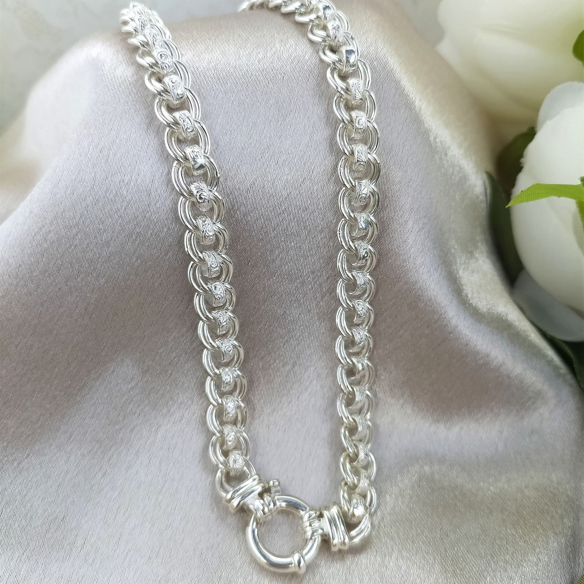 A close up of a silver chain on a white cloth