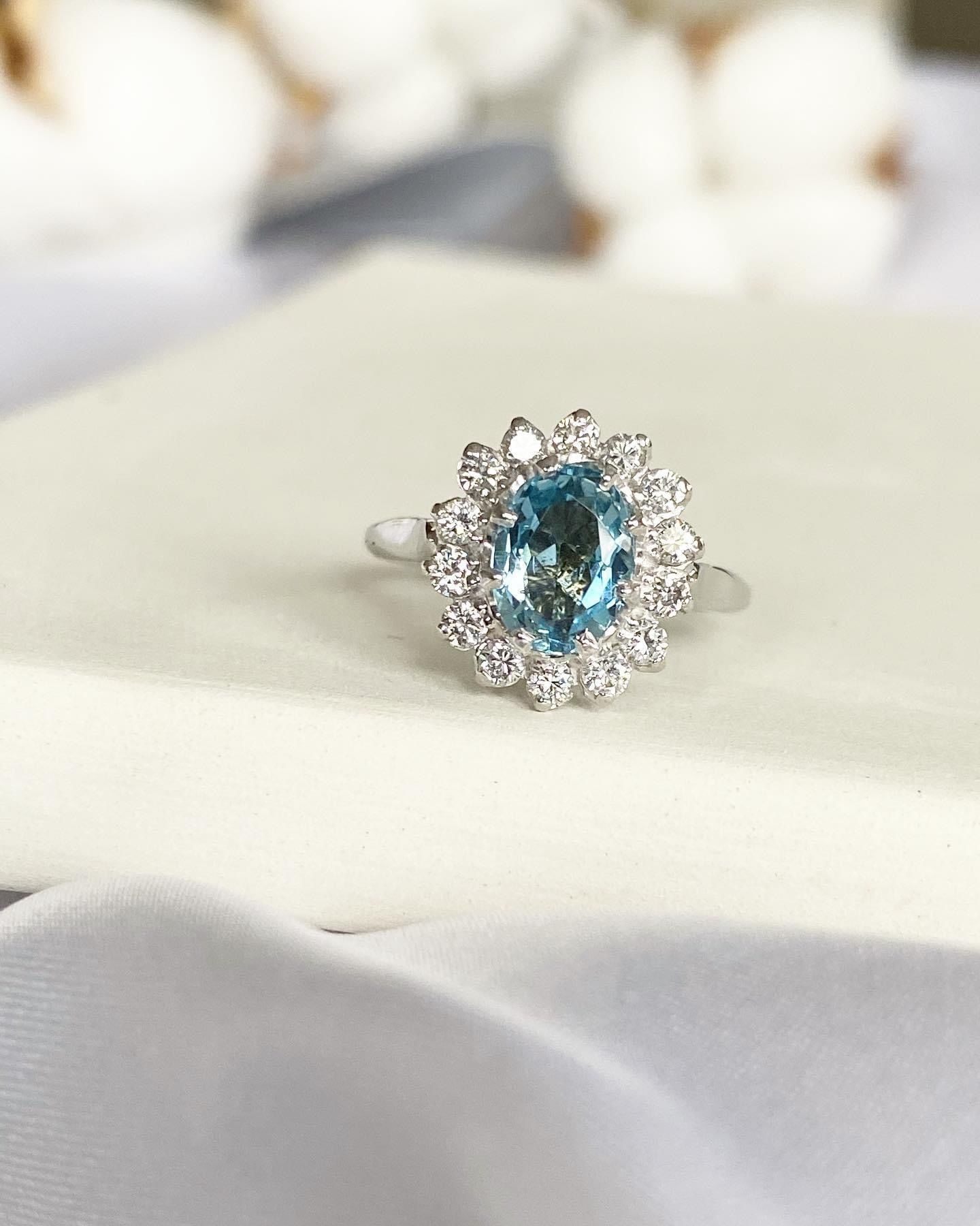 A close up of a ring with a blue stone and diamonds on a table.