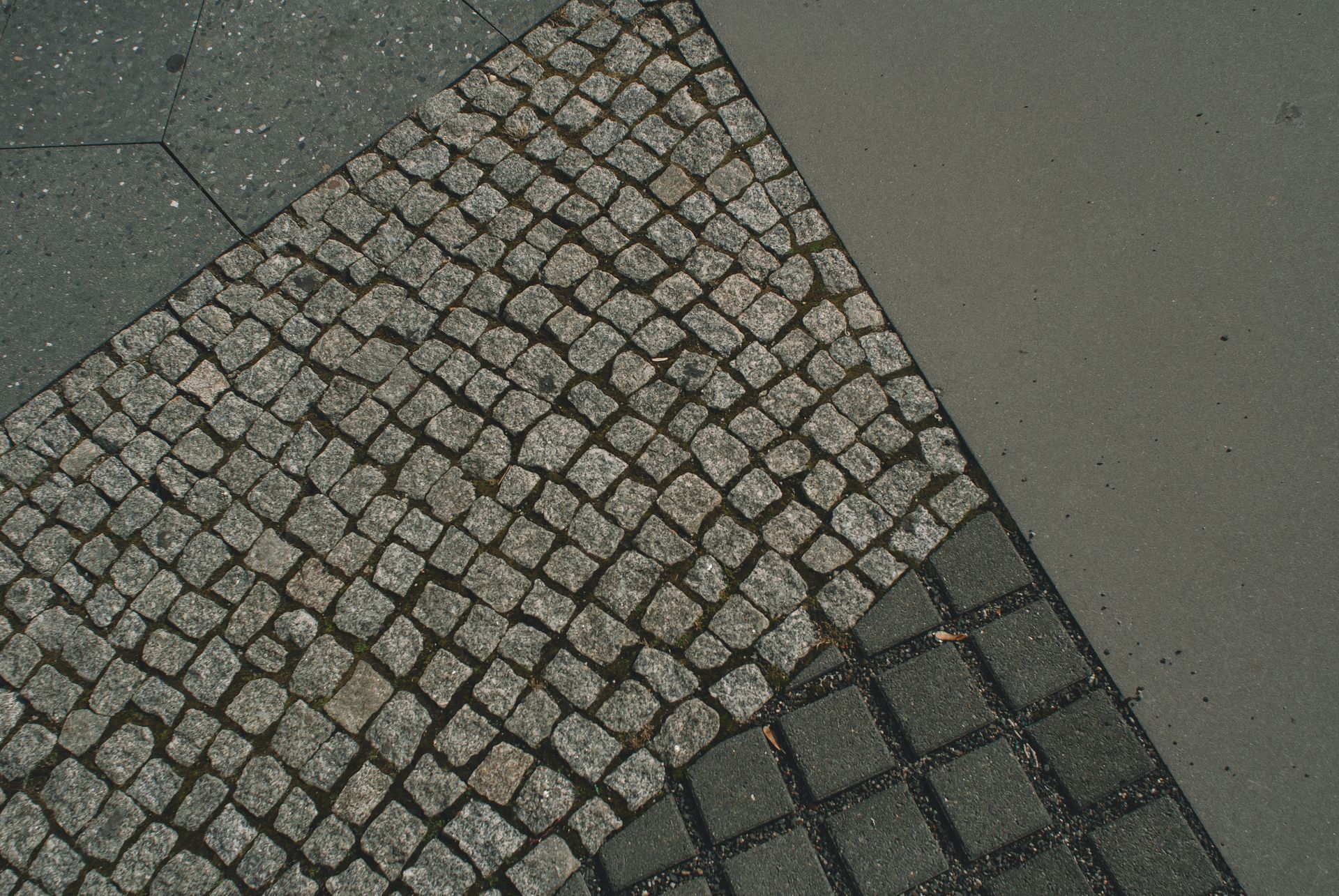 A natural stone sidewalk made from gray and black square floor tiles