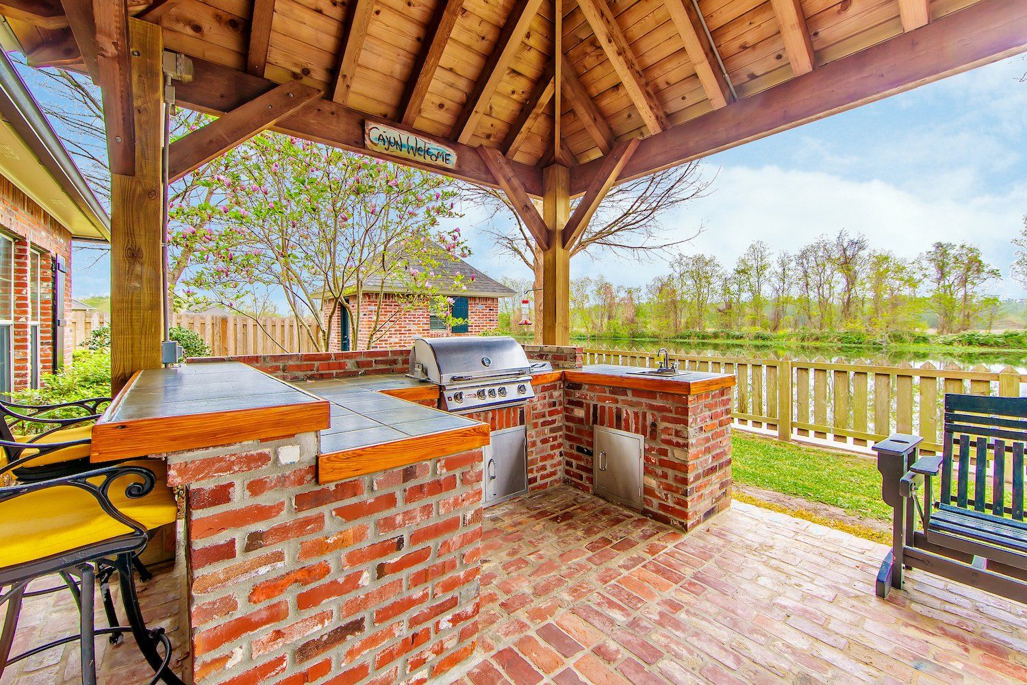 An outdoor kitchen and deck made of elegant brick, featuring a grill, countertops, and seating area, all bathed in warm sunlight.