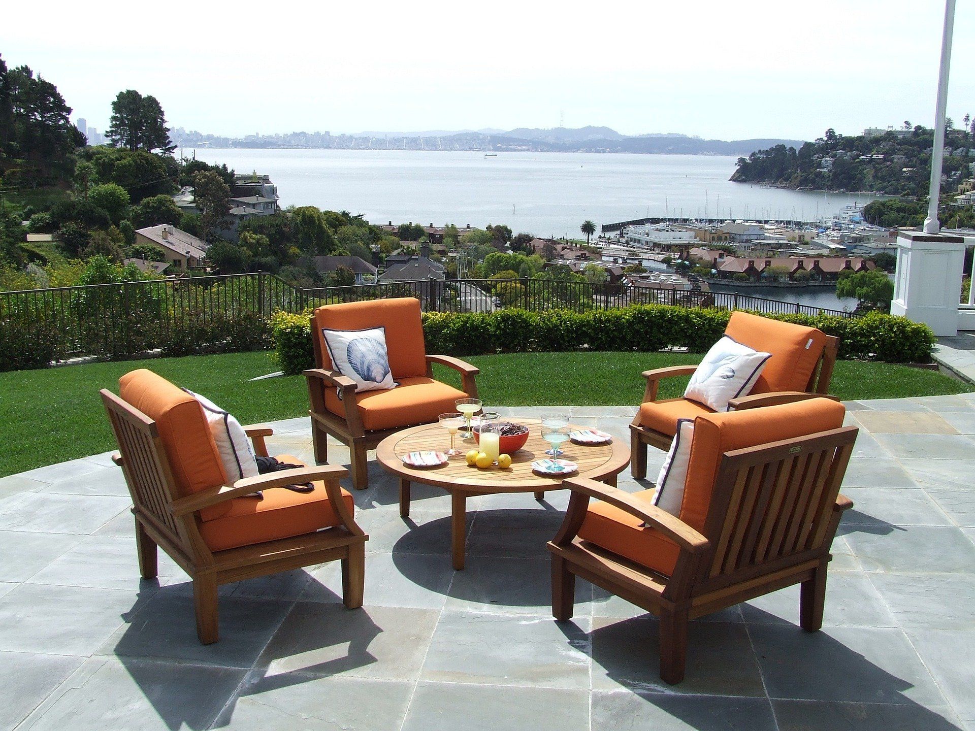 Wooden table and chairs with orange plush cushion, overlooking a stunning cityscape and the serene sea.