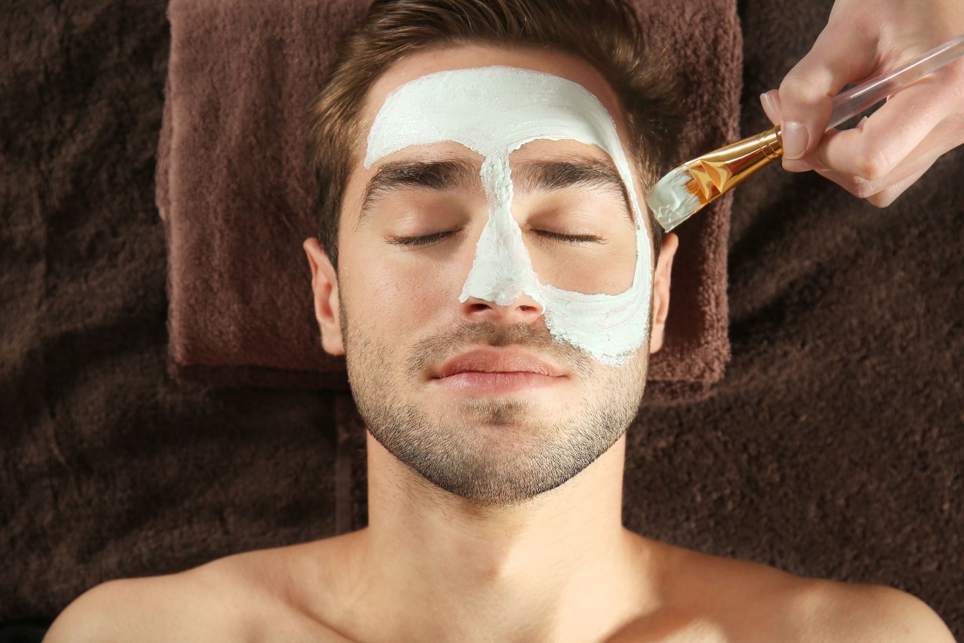 un hombre recibe un tratamiento facial en un spa.