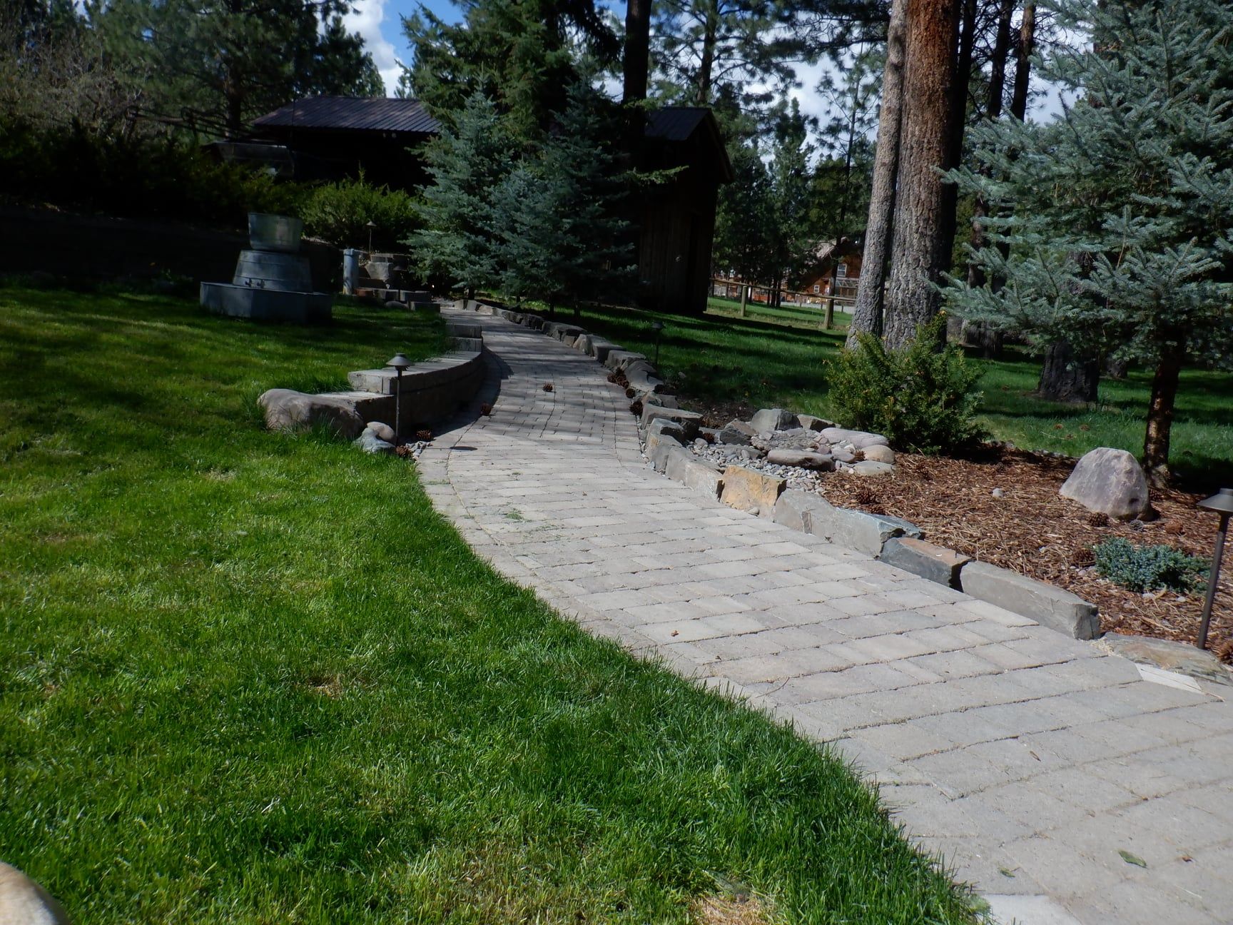 Stone pathway winds through green lawn and trees.
