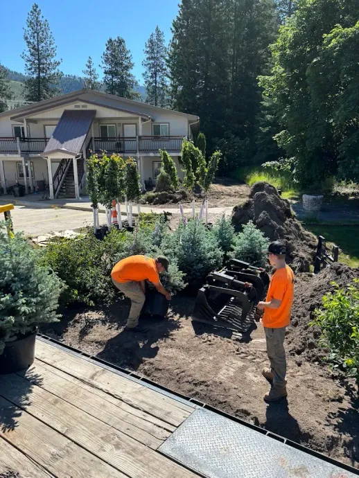 Flagstone pathway under construction; tractor bucket holds material; brown and tan colors.