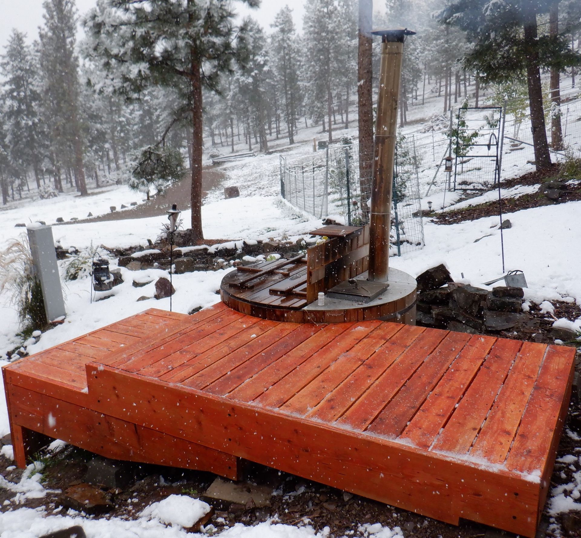 Wooden deck and hot tub in snowy outdoor setting.