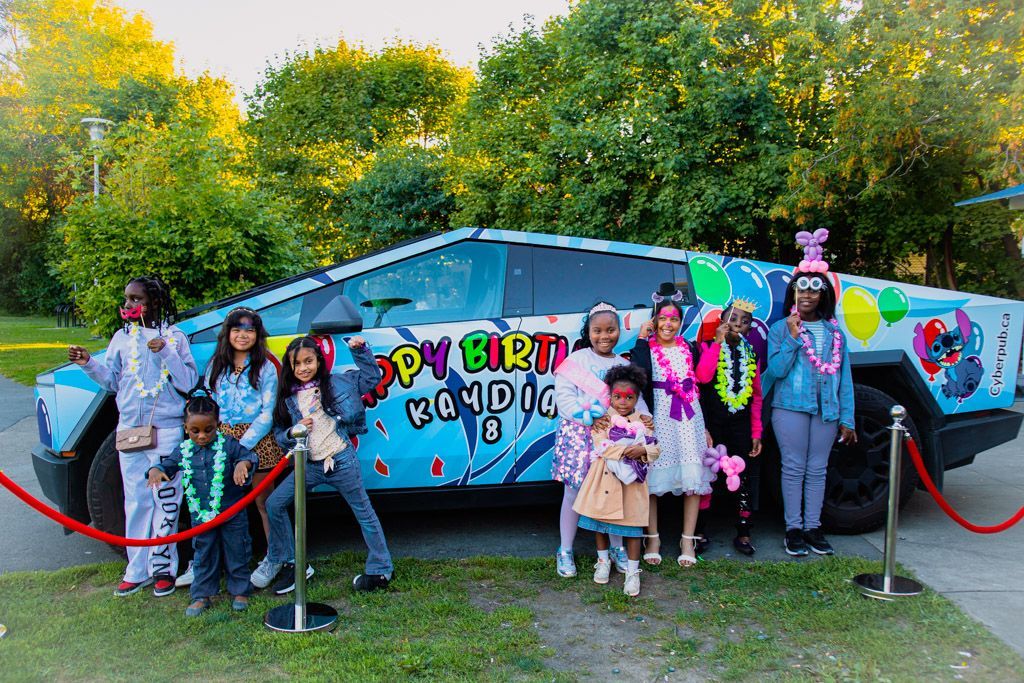 Girl smiling in front of a blue birthday-themed Cybertruck with balloons and 