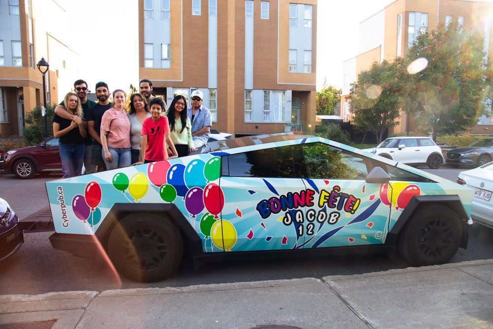 Group poses with a Cybertruck decorated with balloons and