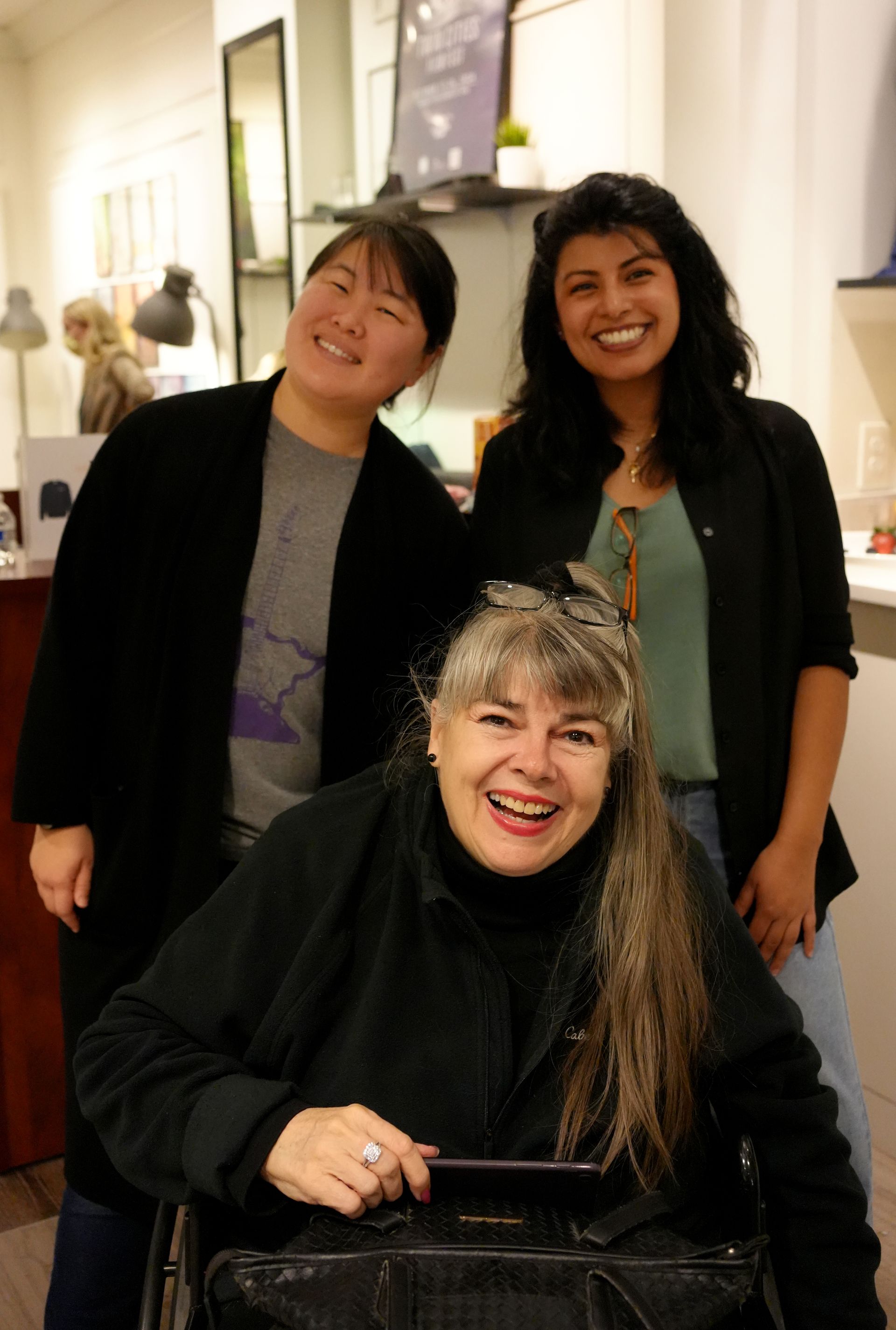 A woman in a wheelchair is posing for a picture with two other women