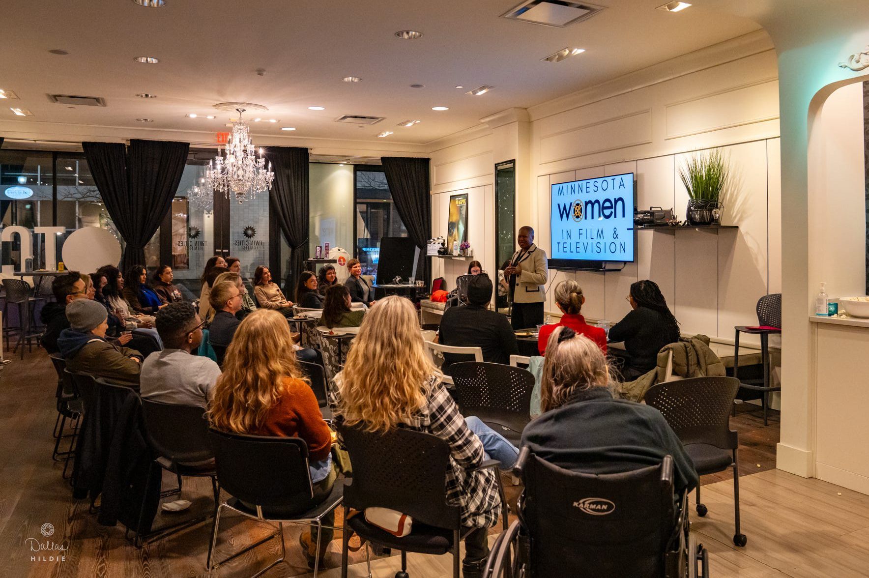 A group of people are sitting in chairs in a room watching a presentation.