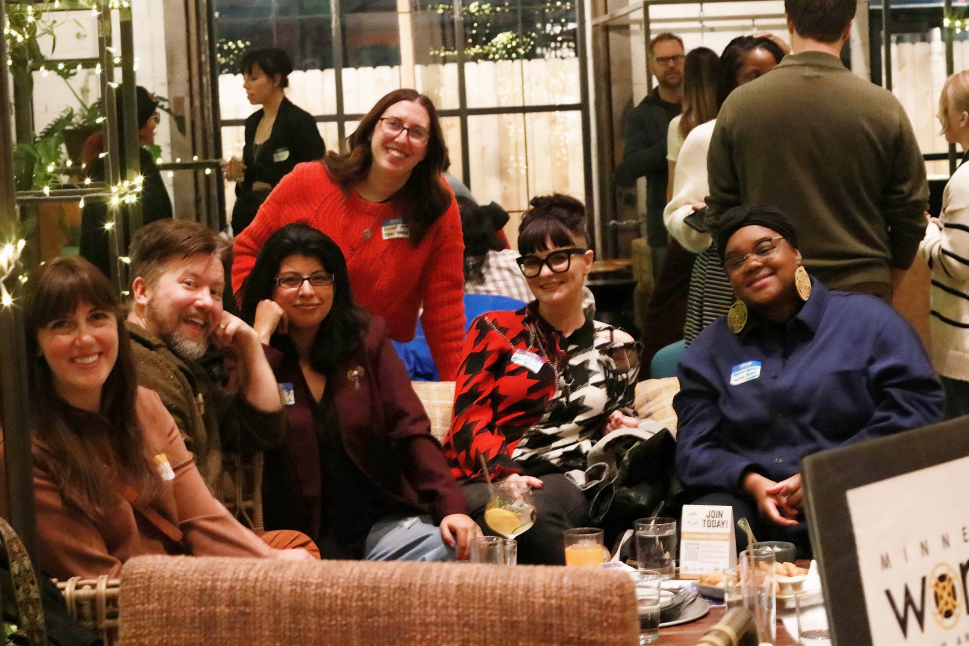 A group of people are posing for a picture while sitting on a couch.