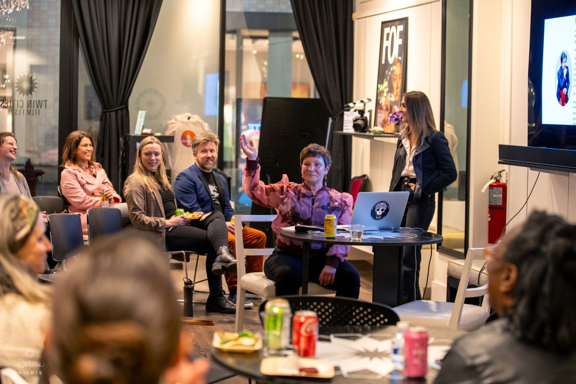 A group of people are sitting around a table watching a presentation.