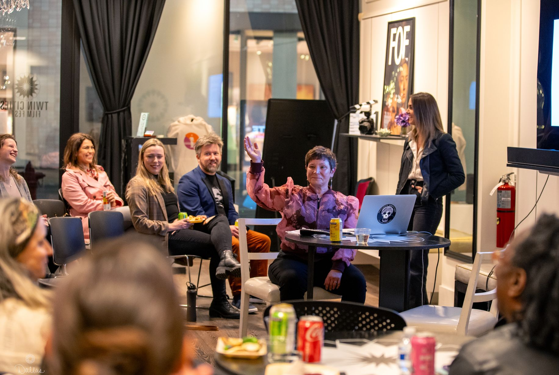 A group of people are sitting around a table watching a presentation.
