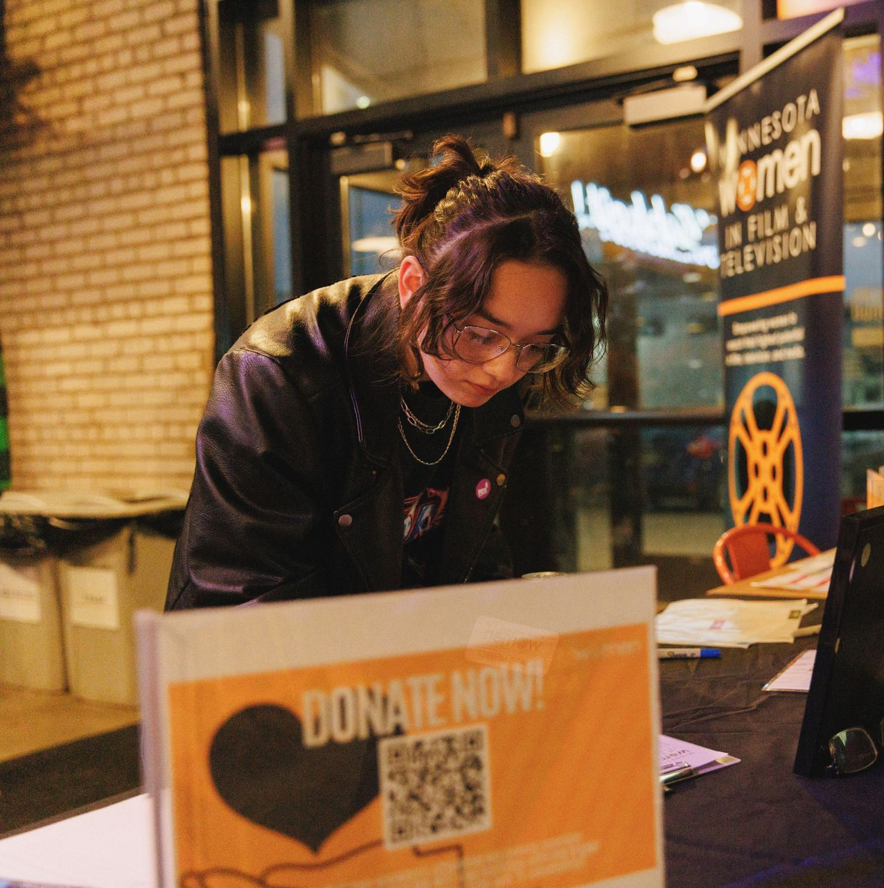 A group of people are standing around a table holding a pizza box.