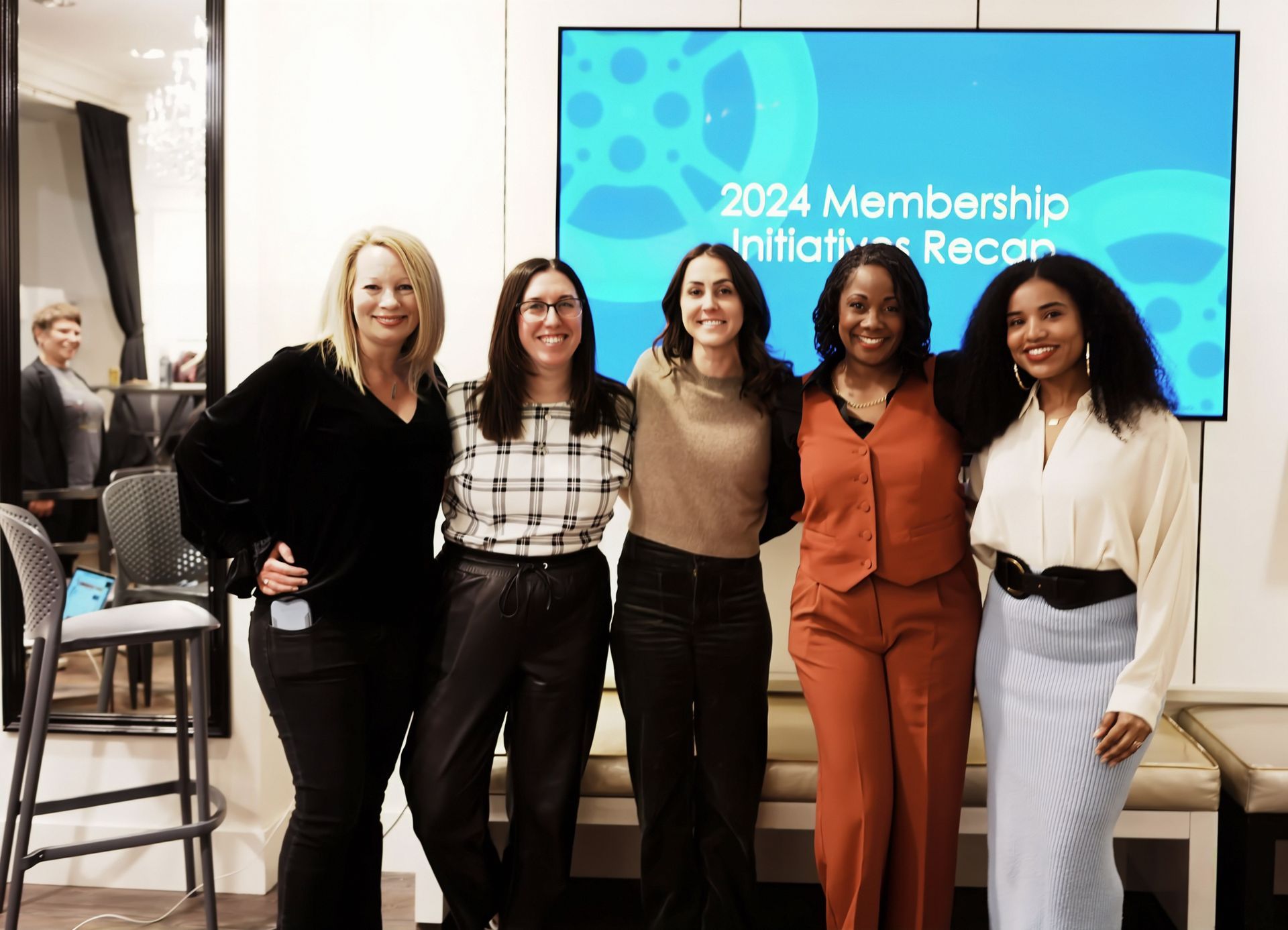 A group of women are posing for a picture in front of a screen.