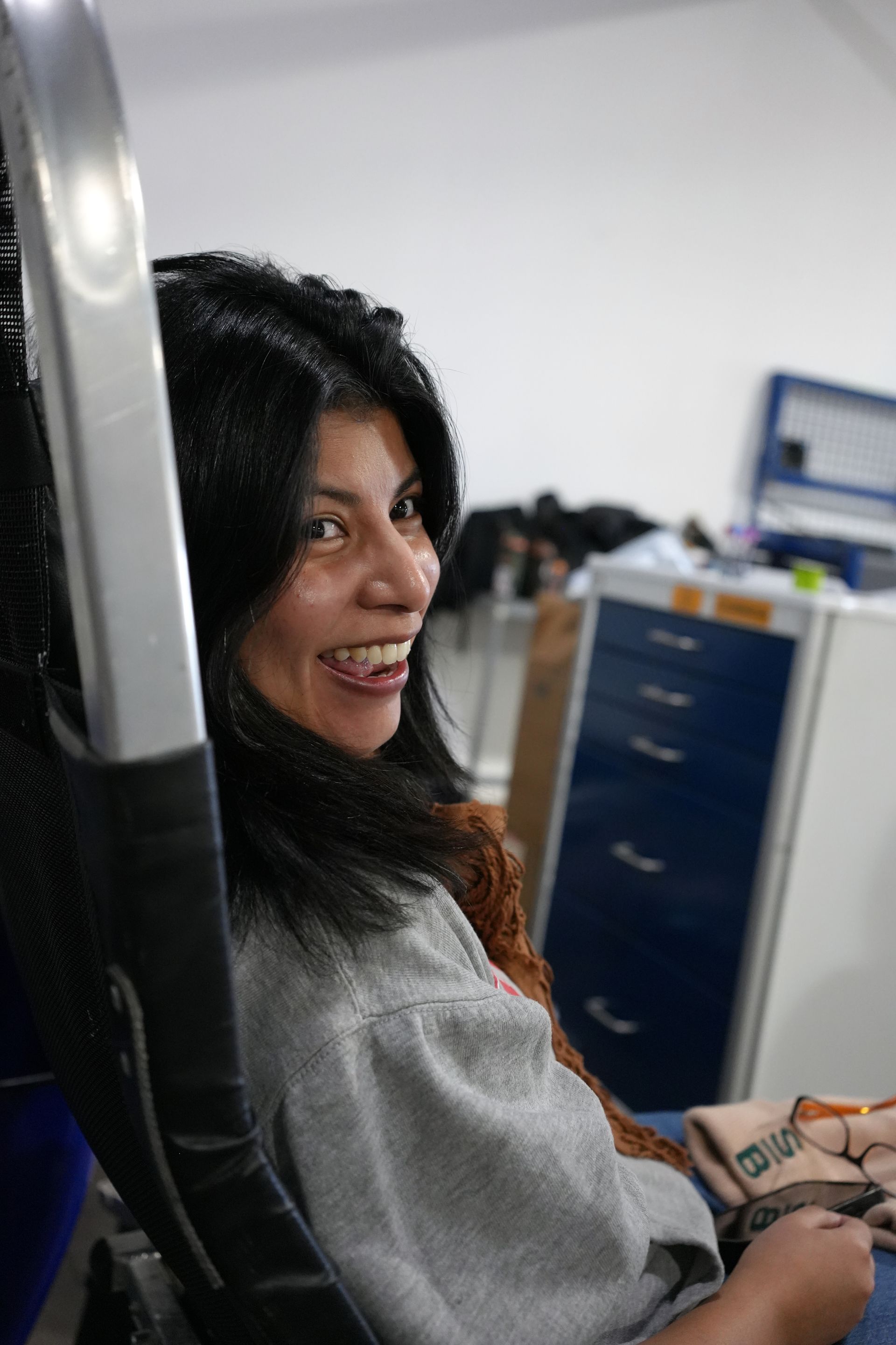 A woman is sitting in a chair and smiling.