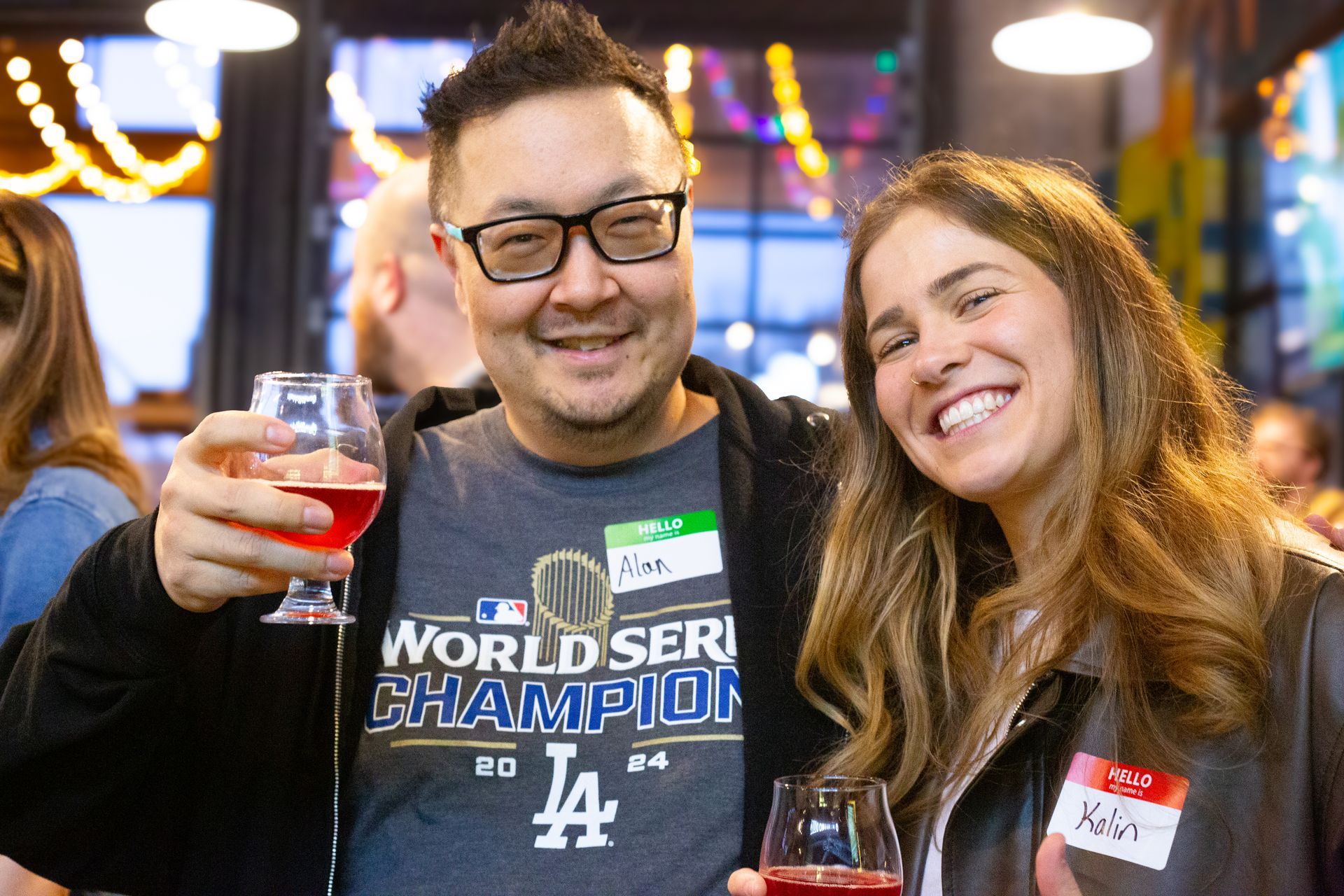 A man and a woman are posing for a picture while holding wine glasses.