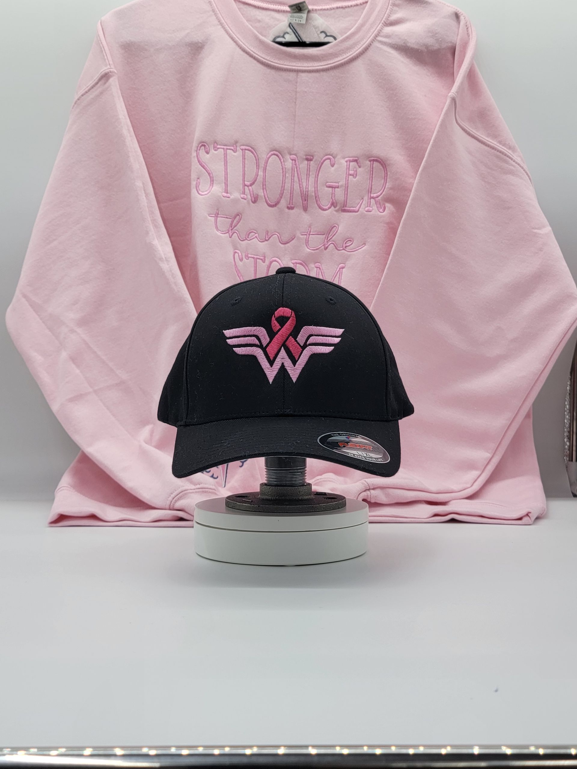 A black baseball cap with a pink ribbon on it