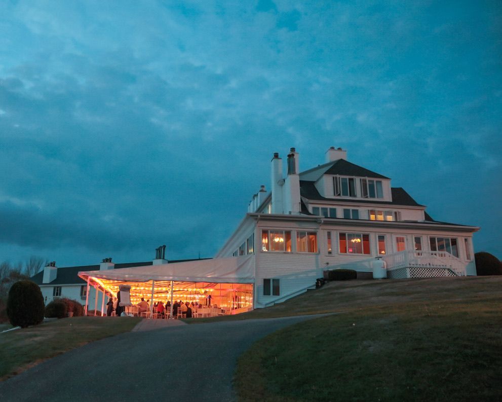 A large white house is sitting on top of a hill at night.