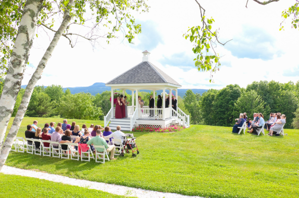 A group of people are sitting in chairs in front of a gazebo.