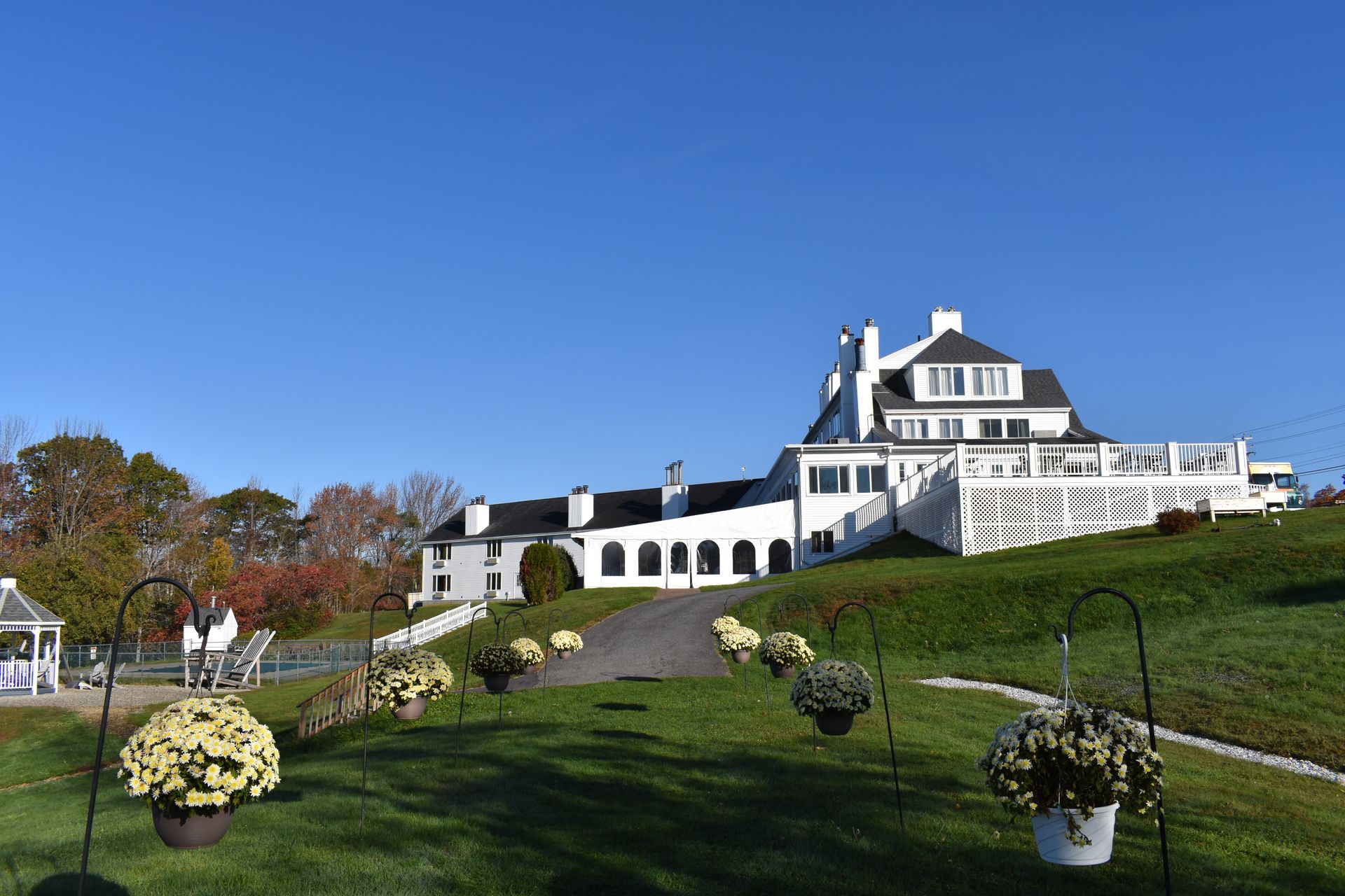 A large white house is sitting on top of a lush green hill.