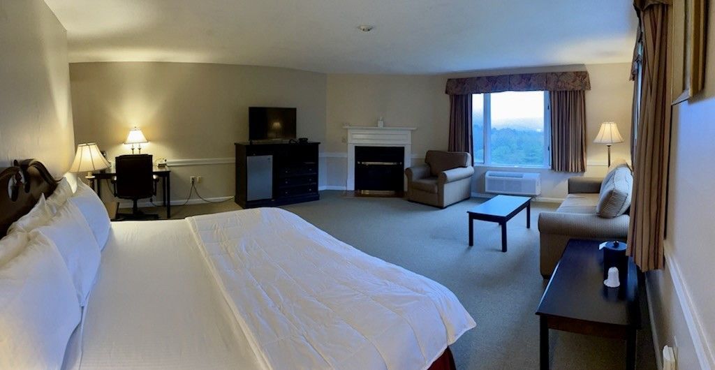 A hotel room with a king size bed , couch , fireplace and television.